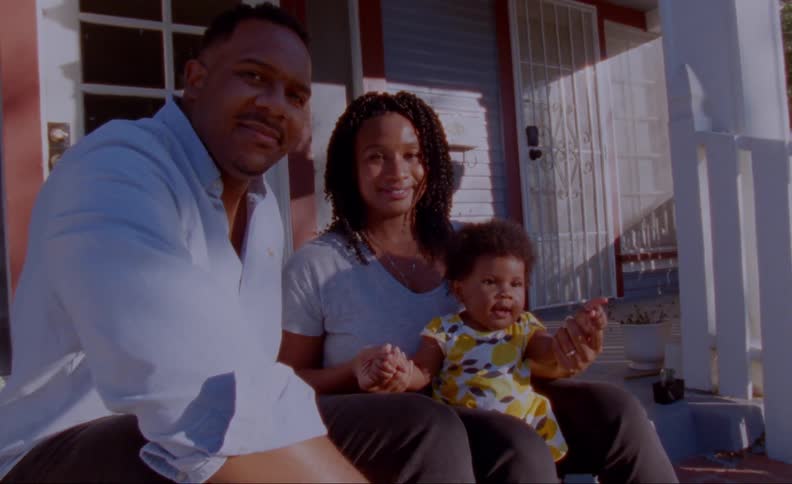 Family sits on front porch steps smiling