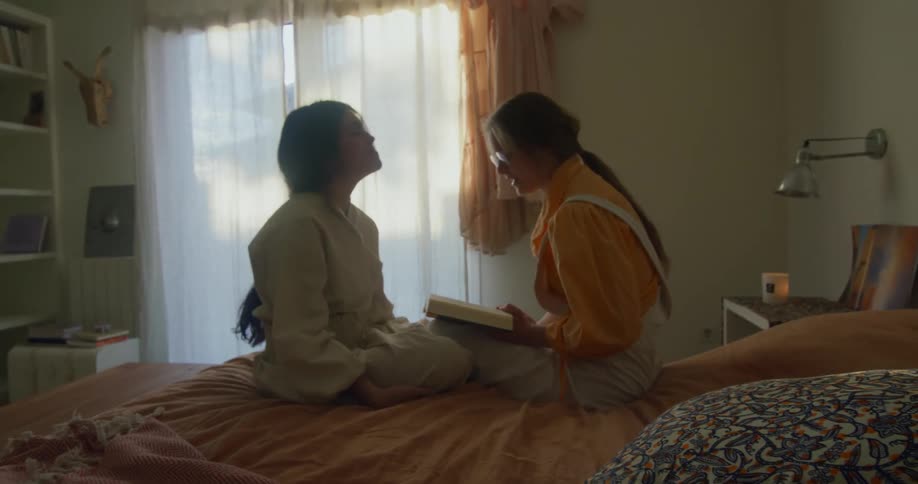 Two friends are sitting on the bed and talking