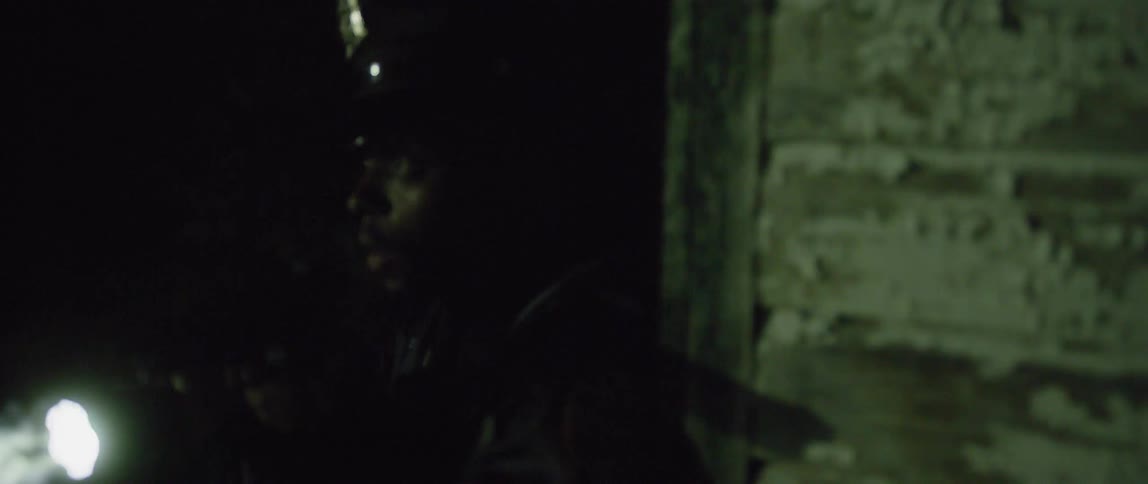 A cop looks around near a dilapidated building