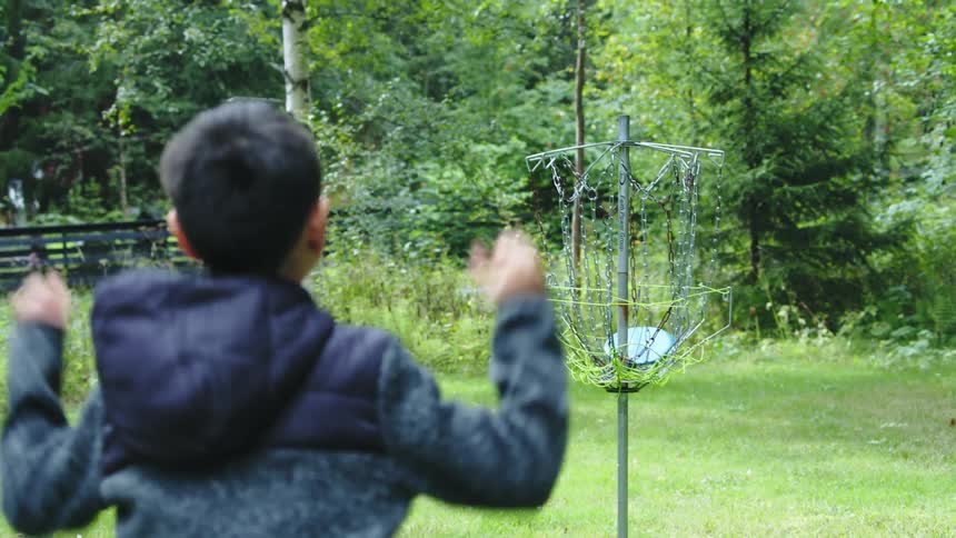 A boy is playing frisbee outdoors in spring