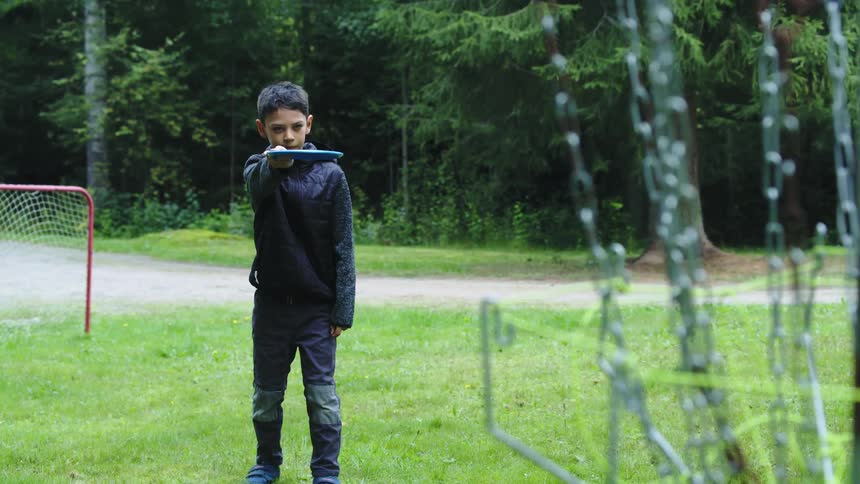 A boy is aiming his frisbee before he throws it and cheers when he hits his target