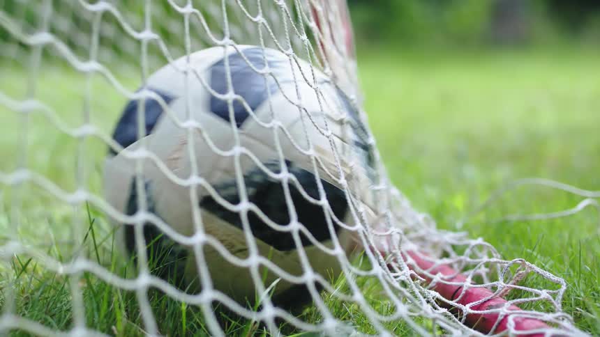 A soccer ball goes into the goal and hits the net