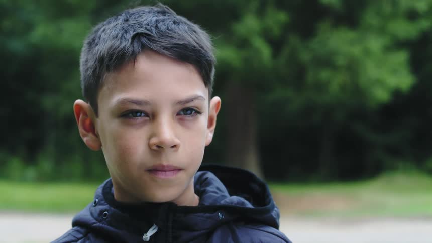 A boy is standing still looking ahead and then he throws something