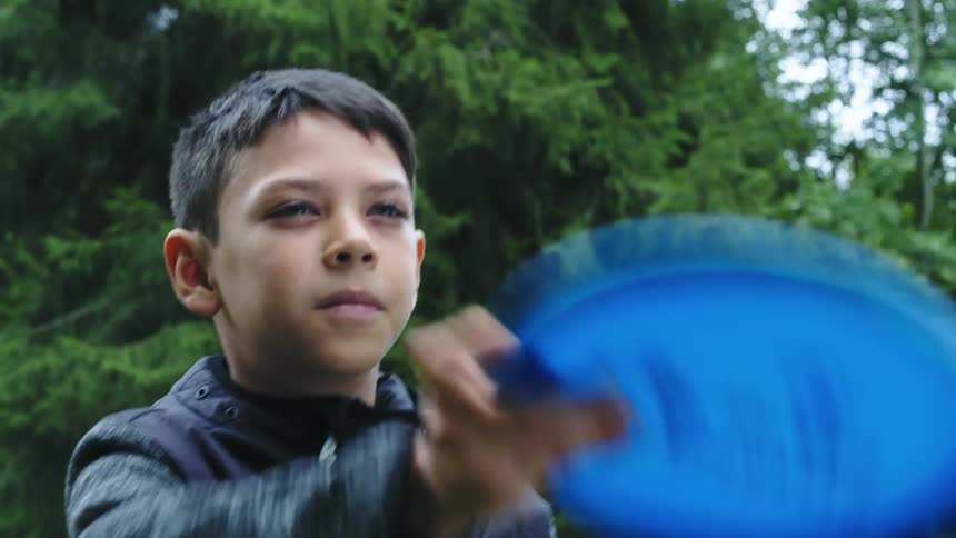 A boy is aiming his frisbee before he throws it and smiles