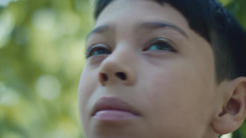 A boy is standing outside looking all around him