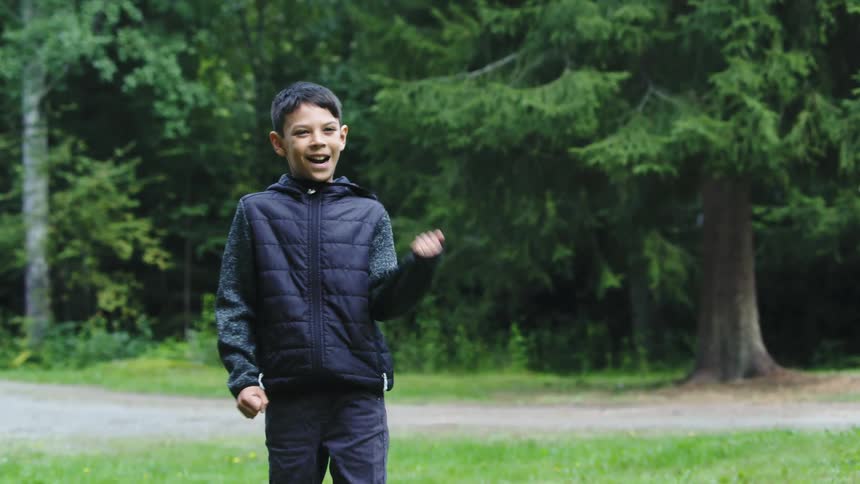 Boy standing in field next to road takes a kick and celebrates his success