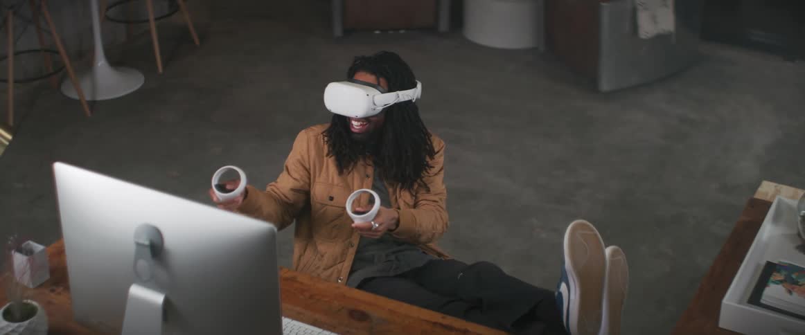 A man smiling while using a virtual reality head set at a desk