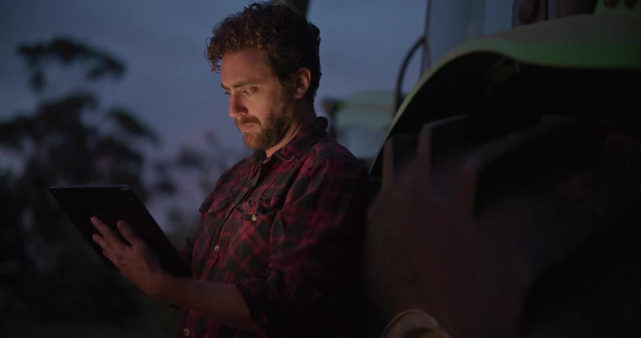 A man is looking at a tablet outdoors at night