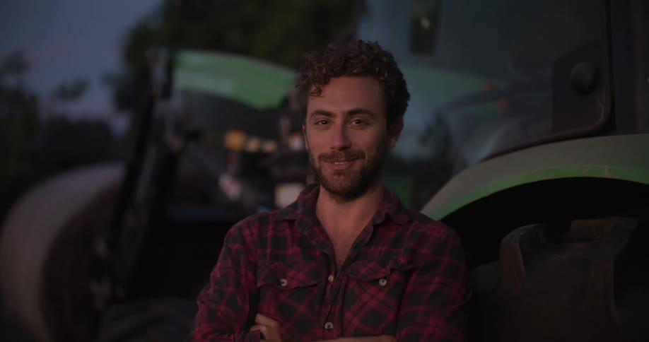 A man stands by the tractor smiling