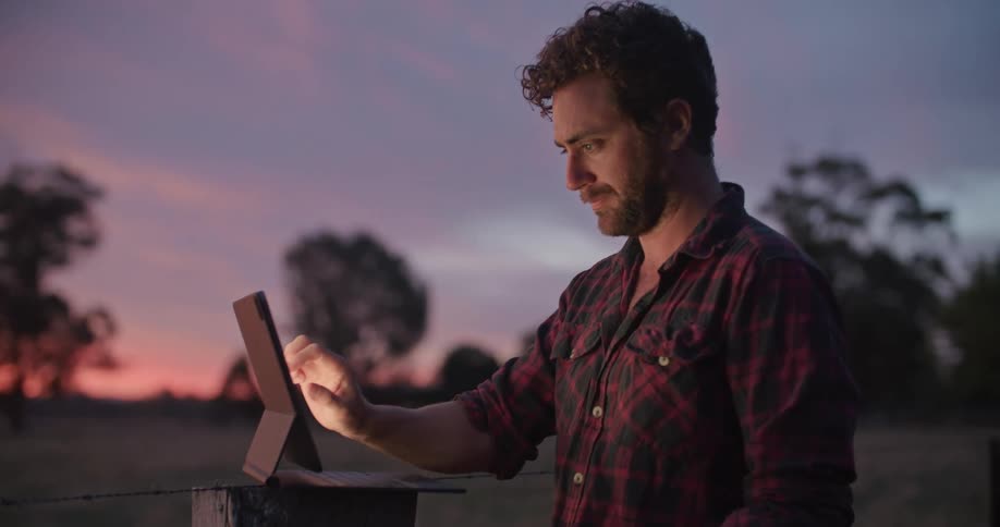 A man is using his tablet on the farm