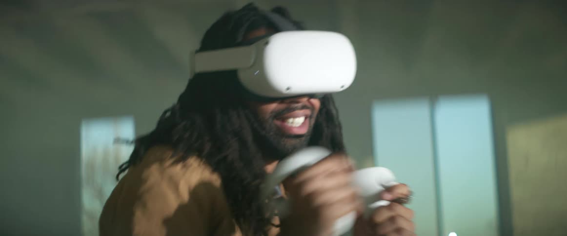 A man with a virtual reality headset on punches his arms as he plays