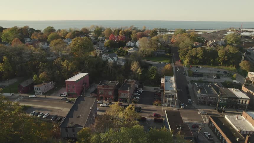 Aerial view of cars driving on a road through a small town near the ocean at sunset