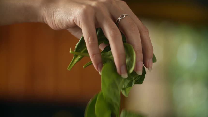A person drops a handful of spinach
