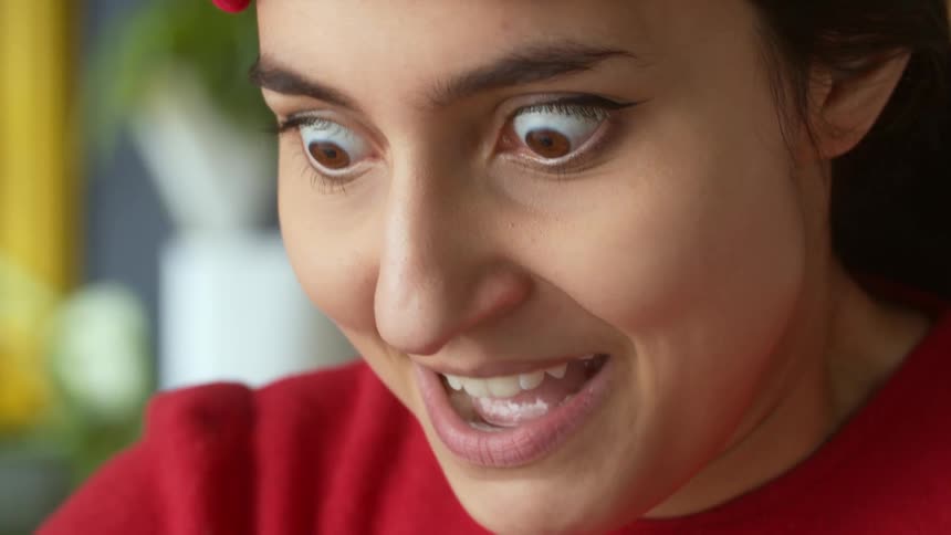 Woman with red headband and shirt pulls a face looking down