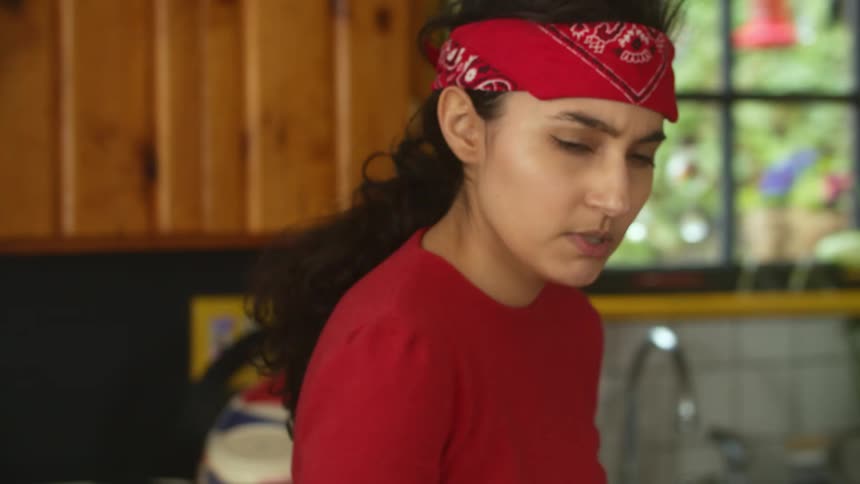 A woman talks while walking back and forth in the kitchen