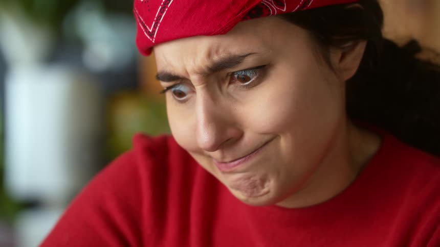 Woman with red headband and shirt pulls a face looking down