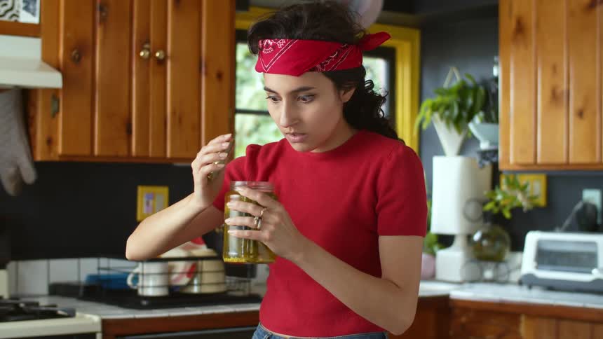 A woman looking surprised after taking the lid off a pickle jar