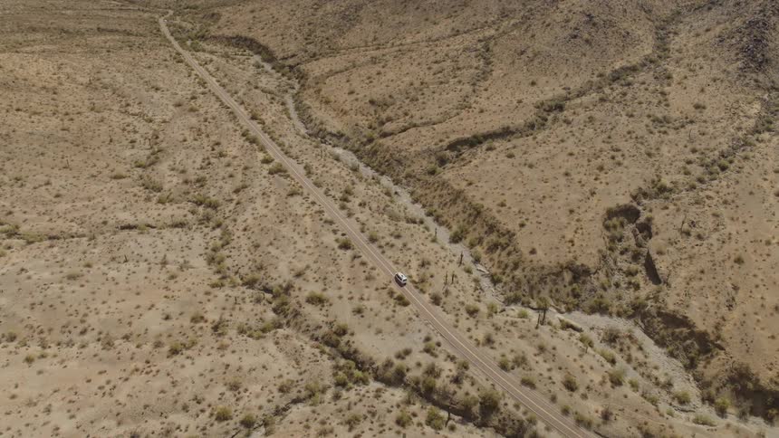 Aerial view of a vehicle traveling on a road through the desert