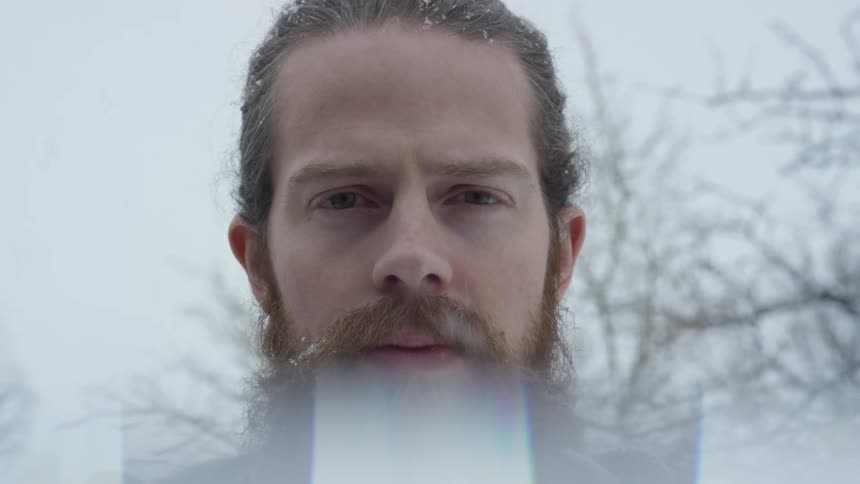 A man is standing outside as it snows