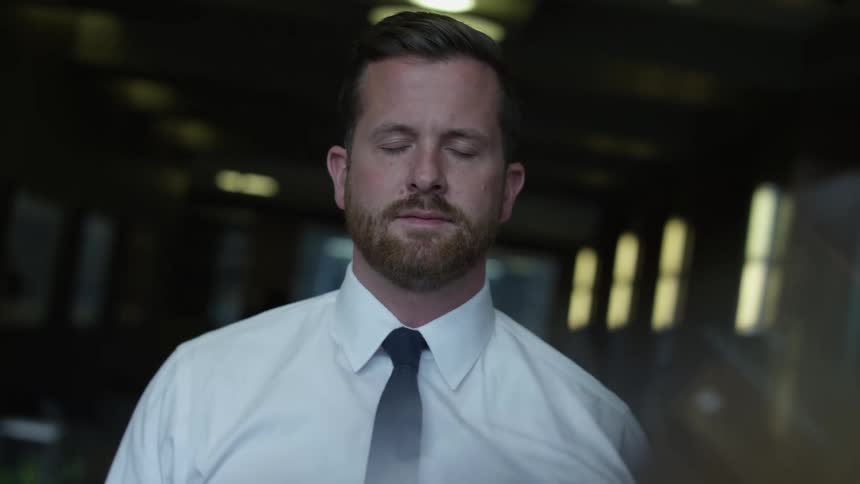 Man with beard shirt and black tie faces the camera with eye contact