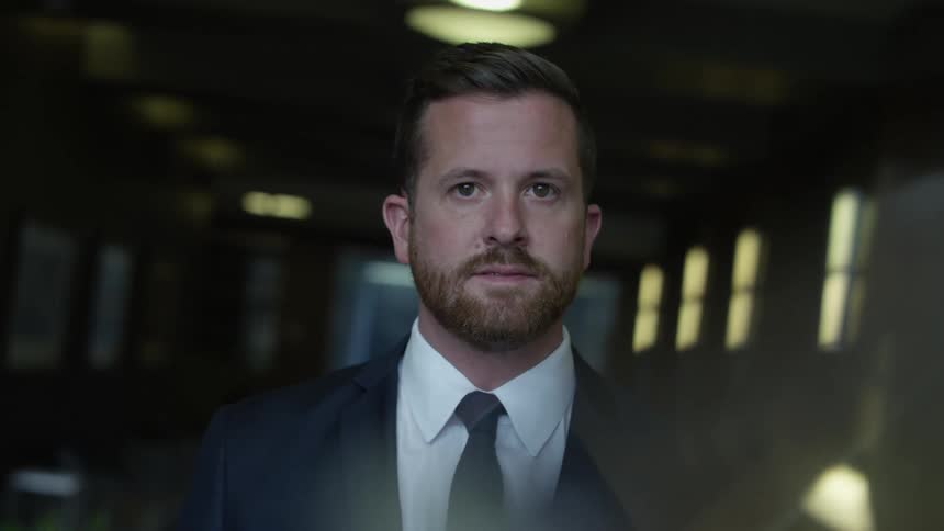A man with short hair and a beard is wearing a suit