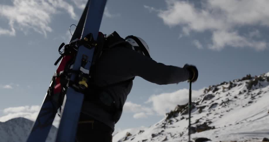 A man walks through snow using ski poles as canes