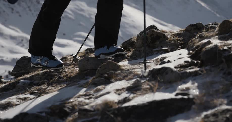 A skier hiking up a rocky mountainside in winter