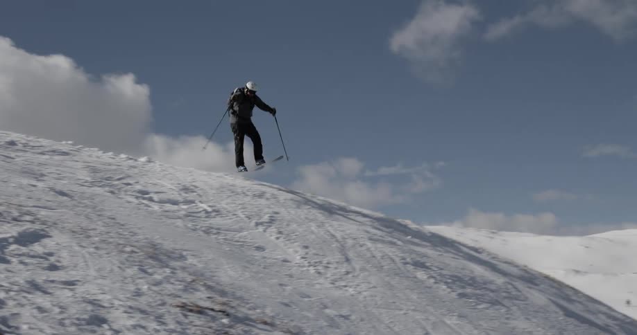 Man with helmet jacket and pants skies down mountain slope