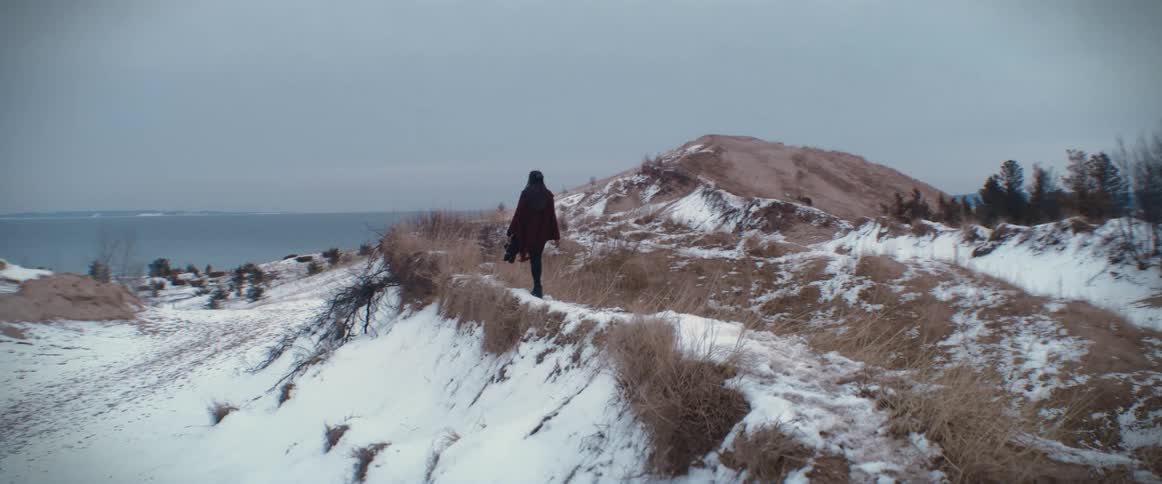 A woman walking on a snowy hill on a breezy winter day
