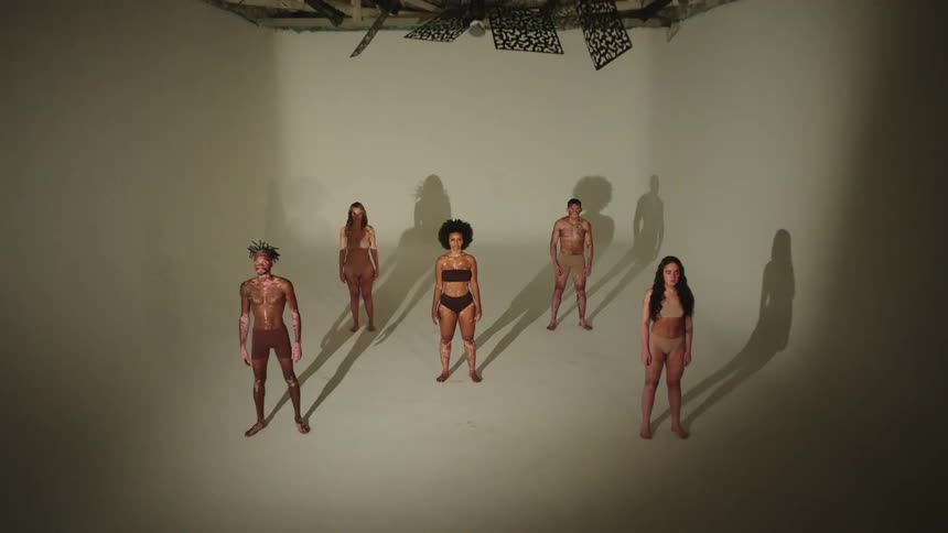 Models pose in skin colored underwear as lights flash on and off in a studio