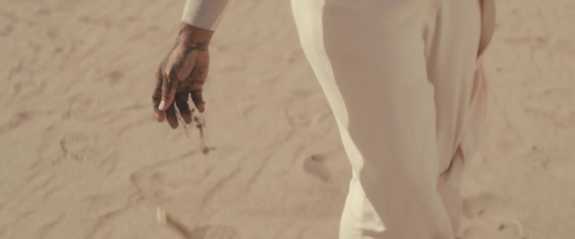 A woman dropping a stick in the sand