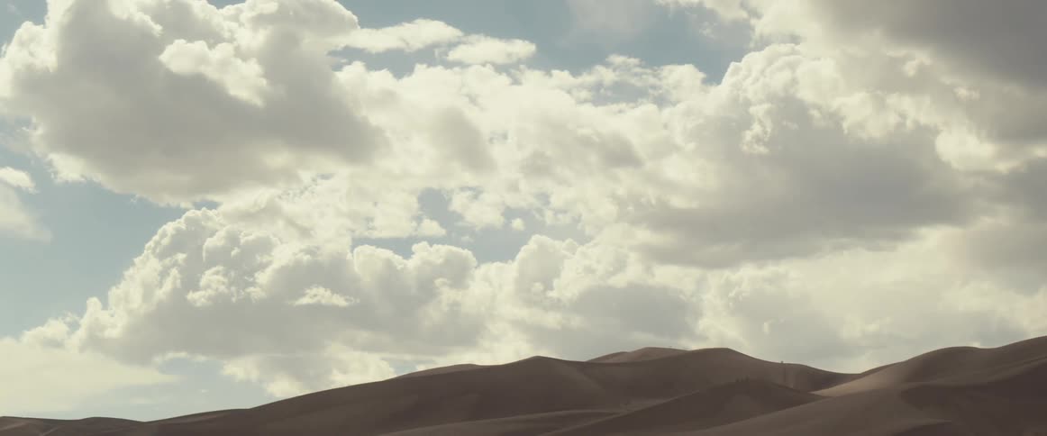 Clouds float over sand dunes in the desert