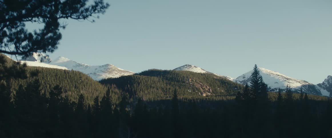 Snow caps the tops of the mountains and hills with trees at the base