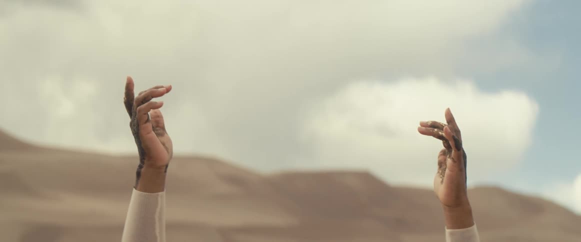 A person is raising their arms outdoors at dusk