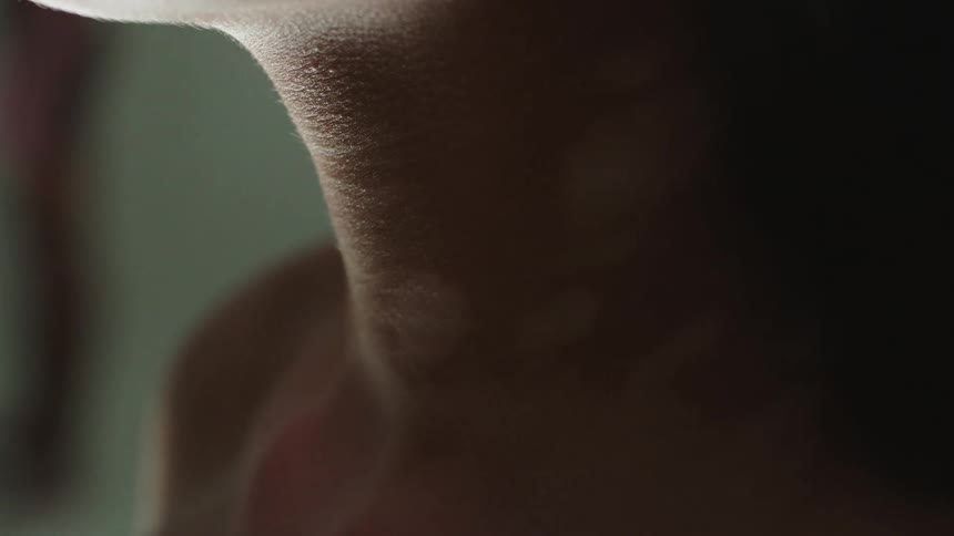 Close up of womans throat and jaw with vitiligo skin and earring in studio