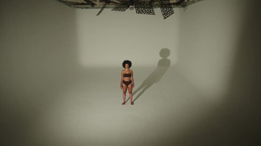 A woman is standing in the room with flashing lights and double shadows