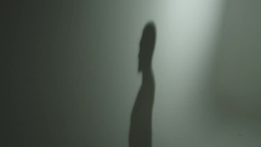 A silhouette of a person is revealed in shadow