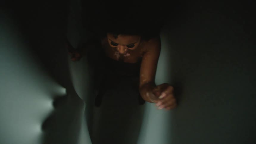 A woman laughs as people reach out to her from behind stretchy fabric
