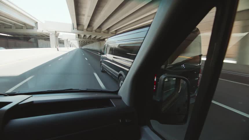 A man is driving a van as another vanpasses him