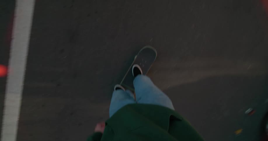 A male sets his skateboard down and skateboards down a street next to parked cars