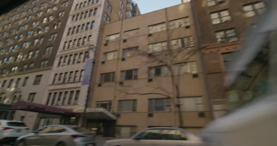 Traveling down a busy city street with cars and trucks parked in front of buildings