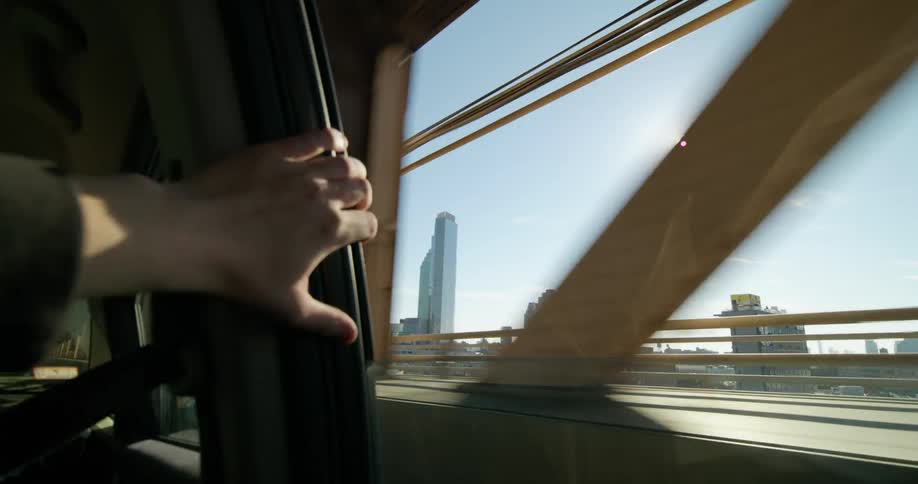 A person puts their hand on the car as it drives on the bridge