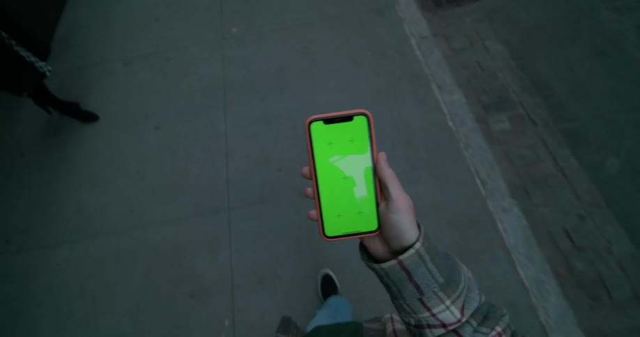 A person walks on the sidewalk using their cell phone