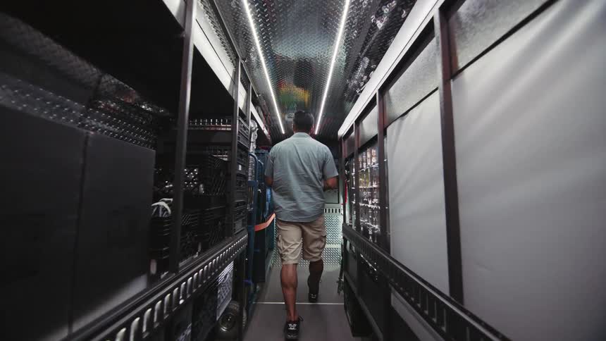 A man walks up a ramp into a van and puts away lighting supplies