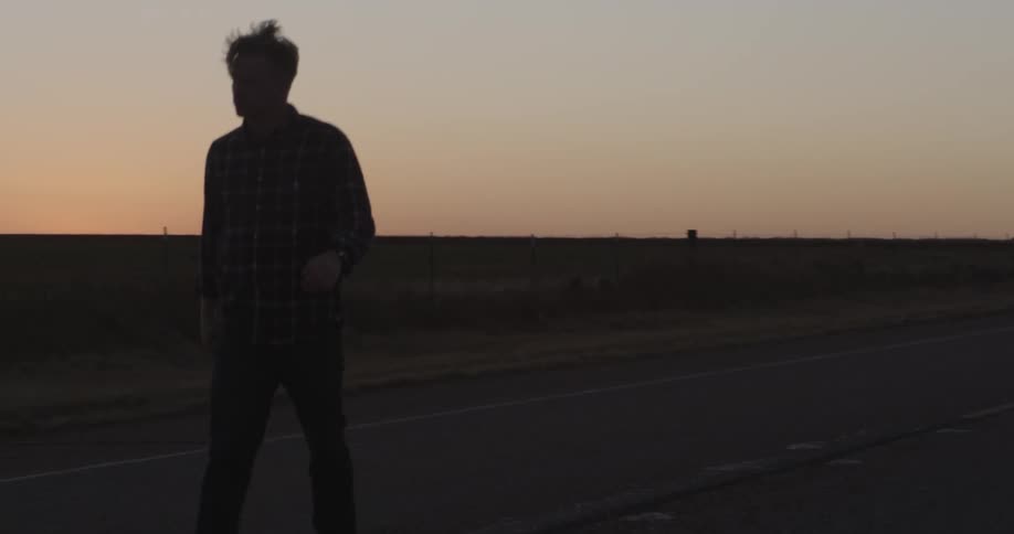 Man walking down a country road after sunset