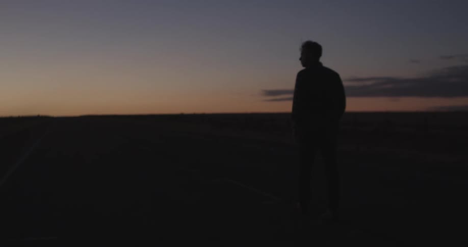 A person walking the beach at sunset
