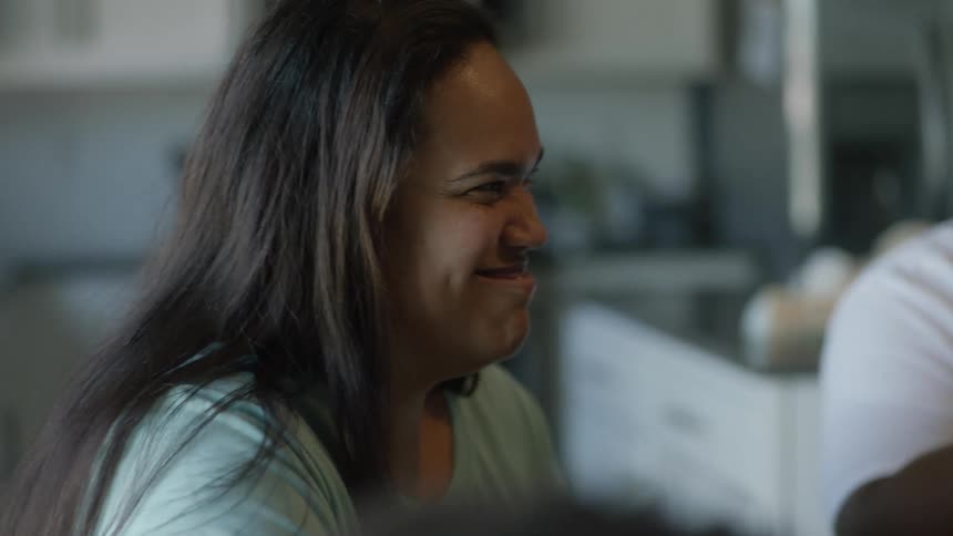 Mother sits with family at table smiling and talking