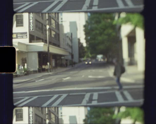A pedestrian crossing a city street as a car drives by