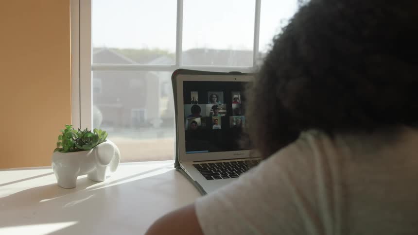 A teenage girl on video chat on a laptop at home