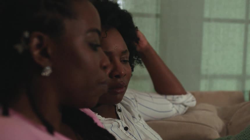 Two women sit on couch while having a discussion